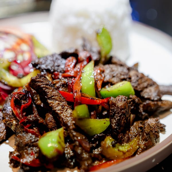Dominican beef dish with red and green peppers, served with white rice and a side salad.