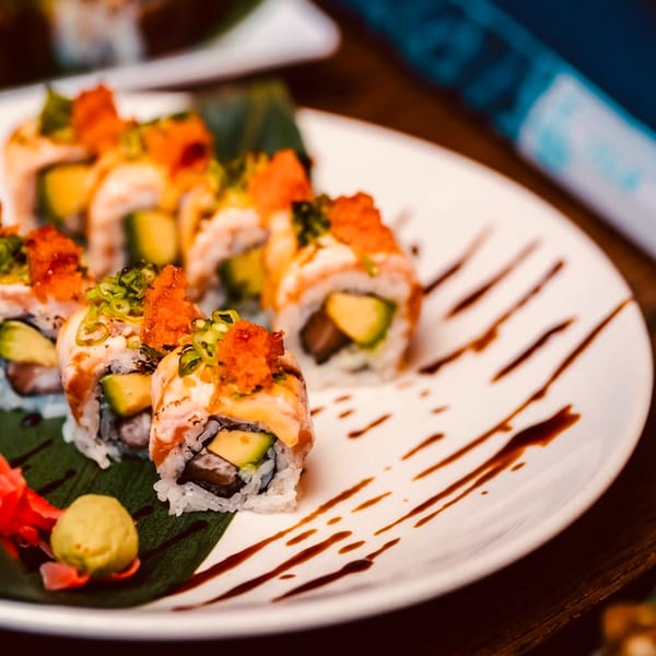 Sushi rolls with avocado, fish roe, and scallions, served with wasabi and pickled ginger.